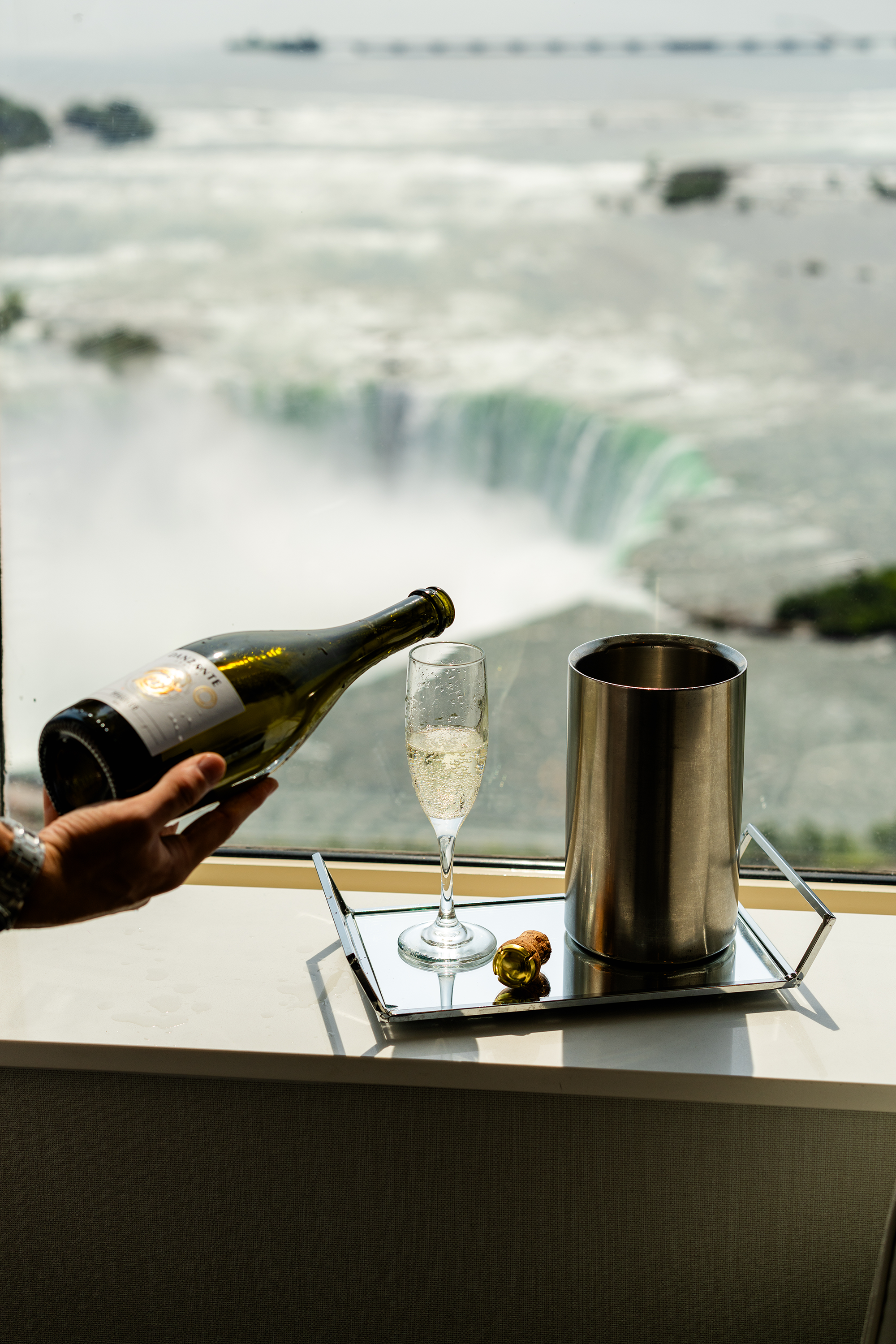 Champagne being poured into glass with a view of Niagara Falls in the background